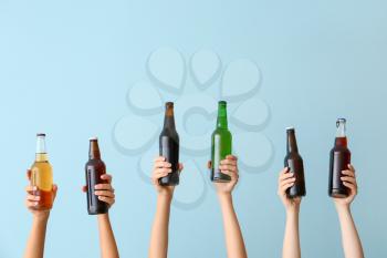 Hands with bottles of beer on color background�