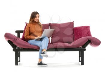 Young woman with laptop sitting on sofa against white background�