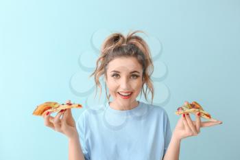 Portrait of beautiful young woman with pizza on color background�