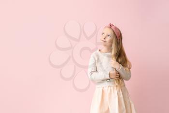 Cute little girl in autumn clothes on color background�