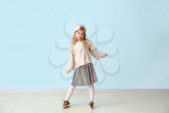 Cute little girl in autumn clothes near color wall�