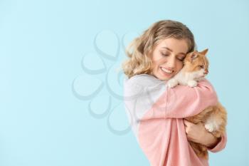 Beautiful young woman with cute cat on color background�