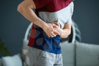 Young man suffering from abdominal pain at home�