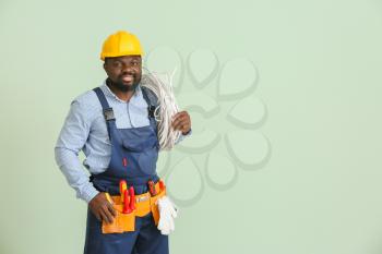 African-American electrician on color background�
