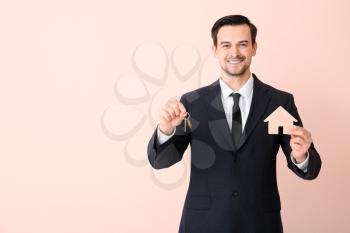 Male real estate agent with key on color background�