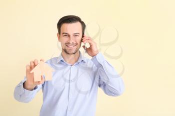 Male real estate agent talking by mobile phone on light background�