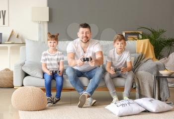 Father and his little children playing video games at home�
