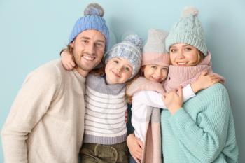 Happy family in winter clothes on color background�