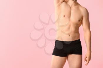 Handsome man in underwear on color background�