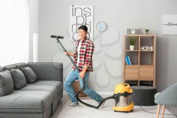 Young Asian man having fun while cleaning floor at home�