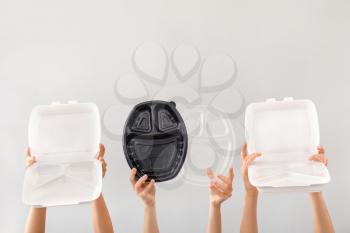 Many hands with containers for food delivery on grey background�