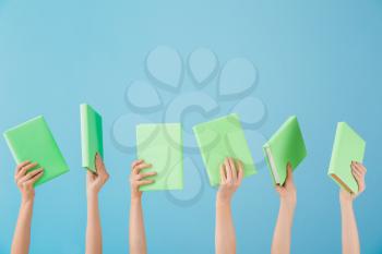 Female hands with books on color background�