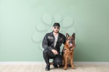 Male police officer with dog near color wall�