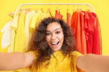 African-American stylist taking selfie near rack with modern clothes�