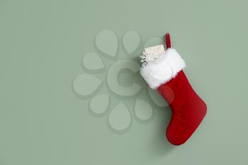 Christmas sock with gift hanging on color wall�