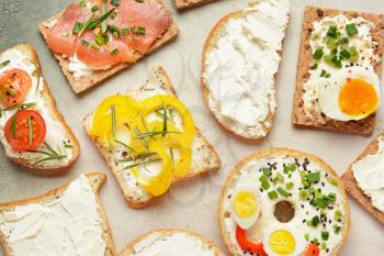 Different sandwiches with tasty cream cheese on light background�
