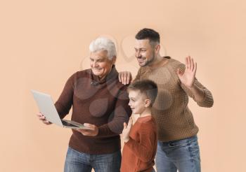 Man with his father and son using laptop on color background�