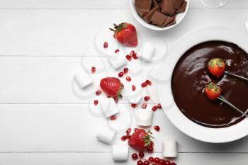 Bowl with tasty chocolate fondue, berries and marshmallow on table�