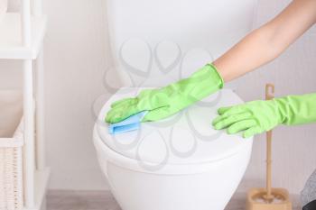 Young woman cleaning toilet in bathroom�