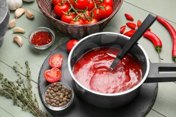 Saucepan with tomato sauce on table�