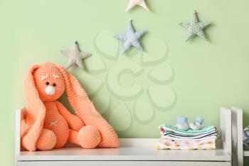 Cuddly toy with baby clothes on table in children's room�