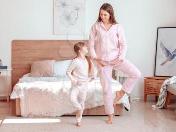Morning of happy mother and her little daughter dancing in bedroom�