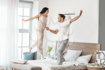 Happy young couple dancing on bed at home�