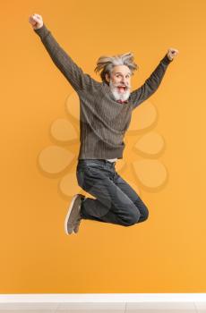 Jumping elderly man on color background�