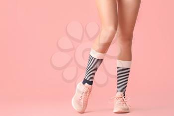 Legs of young woman in socks and shoes on color background�