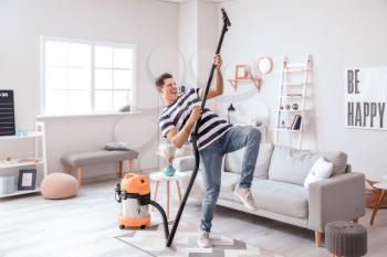 Young man having fun while cleaning floor at home�