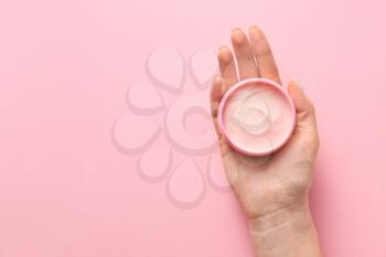 Female hand with jar of cream on color background�