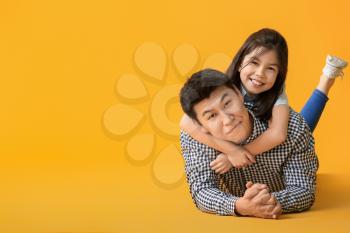 Happy Asian man and his little daughter on color background�