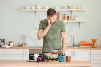 Shocked man looking at pile of dirty dishes on kitchen table�