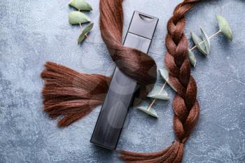 Hair strands and shampoo with herbal extract on grey background�