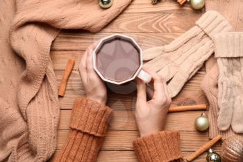 Female hands with cup of hot chocolate on wooden background�