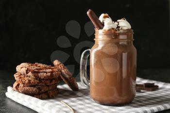 Mason jar of hot chocolate with cookies on dark background�