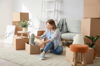 Young woman unpacking moving boxes in her new home�