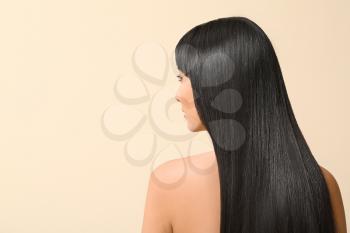 Young Asian woman with beautiful long hair on color background�