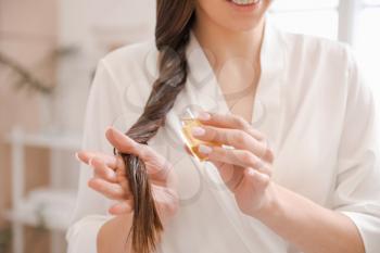 Young woman using cosmetics for hair at home, closeup�