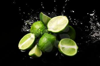 Fresh limes with water splashes on dark background�