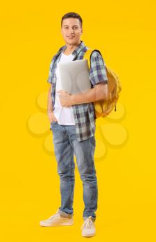 Male student with laptop on color background�