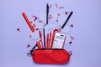 Pencil case and school stationery on color background�