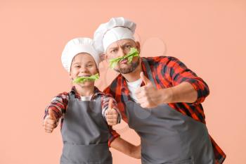 Funny male chef and his little son on color background�