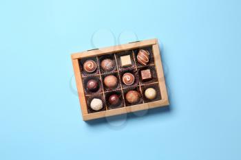 Box with delicious chocolate candies on color background�