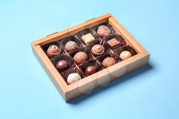 Box with delicious chocolate candies on color background�