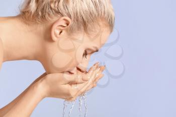 Woman washing face against color background�