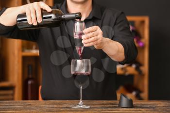 Man with bottle of wine, glass and aerator in cellar�