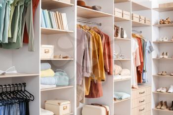 Big wardrobe with different clothes and accessories in dressing room�