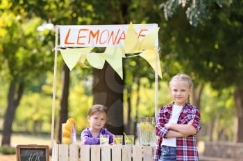 Little girls trying to sell lemonade in park on summer day�