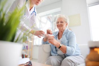 Doctor giving medicine to senior woman at home 